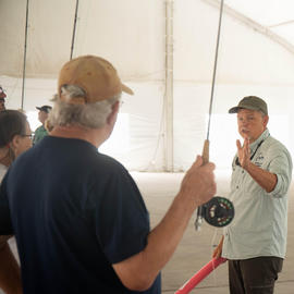 An instructor from Good Fly teaches an attendee on the proper fly casting technique